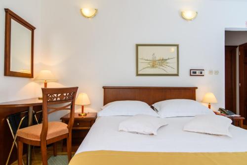 a bedroom with a bed and a desk and a chair at Heritage Hotel Vila Sikaa in Trogir