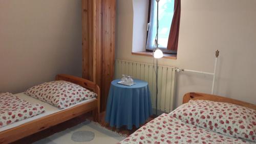 エゲルにあるVécsey Apartmanのベッドルーム1室(ベッド2台、窓のある青いテーブル付)
