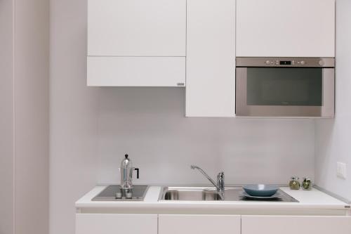 Una cocina blanca con fregadero y microondas. en Trani Rent Rooms, en Trani