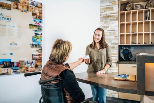a woman sitting at a table talking to a customer at Ferienwohnungen Guthof in Schattwald