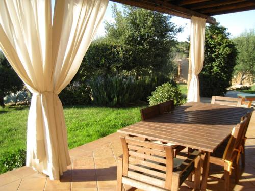 una mesa de madera y sillas en un patio en Le Tre Pietre, en Baja Sardinia