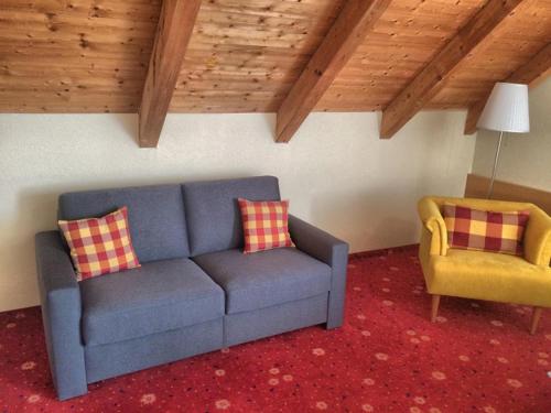 a living room with a blue couch and a yellow chair at Akzent Hotel Höhenblick in Mühlhausen im Täle