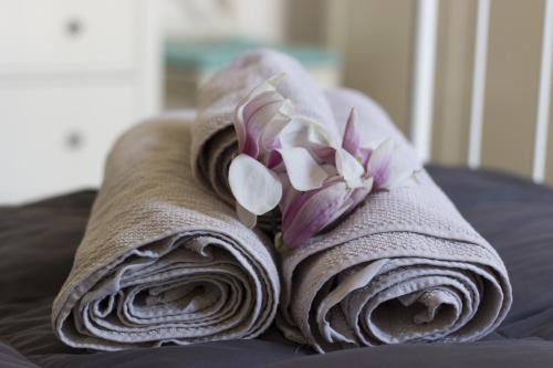 2 toallas enrolladas con flores encima de una cama en Prada District Milan Apartment, en Milán