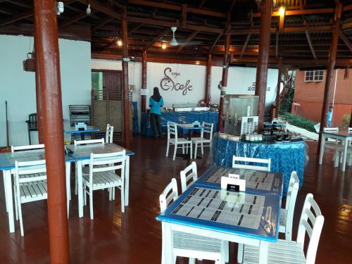 a restaurant with tables and chairs and a woman in the background at Senja Bay Resort in Perhentian Island