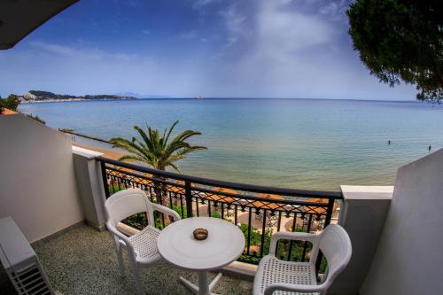 a balcony with a table and chairs and a view of the ocean at Chryssi Akti Hotel in Argasi