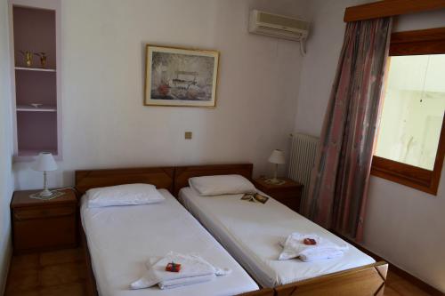 two twin beds in a room with a window at Bellevue Apartments in Sitia