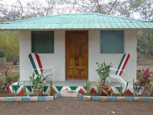 a small cottage with two chairs and a door at Hostal Villas Mexico in San Juan del Sur