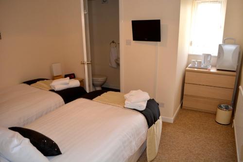 a hotel room with two beds and a television at Winston Guesthouse in Bicester