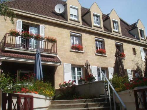 un bâtiment avec des parasols et des fleurs devant lui dans l'établissement Logis Hôtel-Restaurant Les Airelles, à Neufchâtel-en-Bray