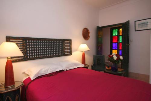 a bedroom with a red bed and a stained glass window at Riad Celia in Marrakech