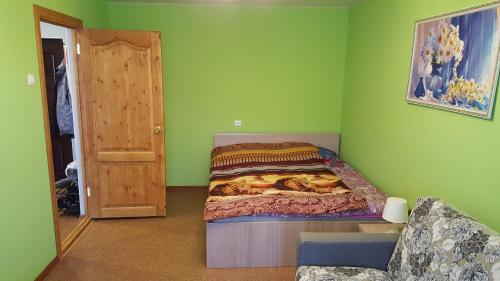 una piccola camera con un letto su una parete verde di Apartment GrInn 45 on Kommunalnaya a Pskov