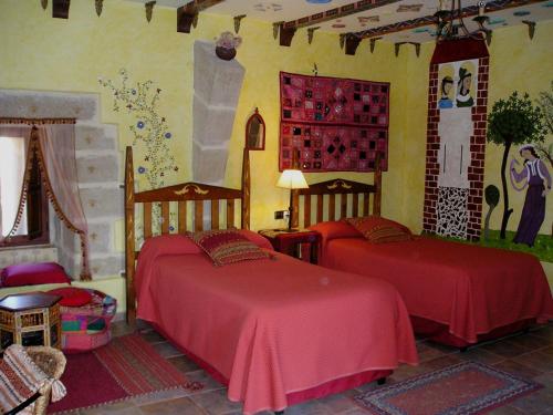 a bedroom with two beds with red sheets at TORRE FUERTE Siglo XIII in Baños de Rioja