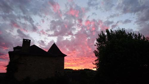 a sunset with a building in the foreground at Hotel La Bastie d'Urfé in Naussac