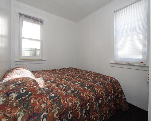 Cama en habitación blanca con 2 ventanas en Shore Beach Houses - 38 D Lincoln Avenue, en Seaside Heights
