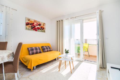 a living room with a yellow couch and a balcony at Apartments Rakuljic in Podstrana
