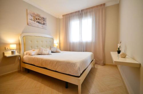 a bedroom with a white bed with a window at Aparthotel Ola Blanca in Cala de Finestrat