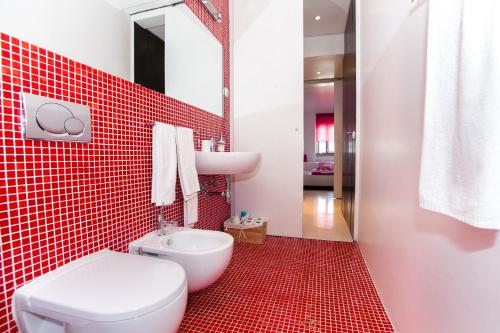 a red tiled bathroom with a toilet and a sink at Ana's Design Apartments in Lisbon