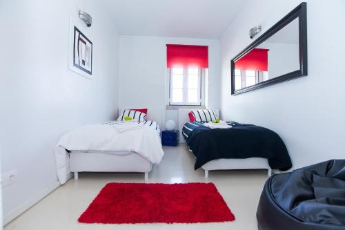 a bedroom with two beds and a red rug at Ana's Design Apartments in Lisbon