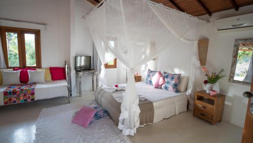 a bedroom with a bed with a mosquito net at Pousada Jardim Das Margaridas in Trancoso