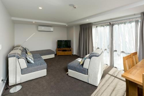 ein Wohnzimmer mit zwei Stühlen und einem Flachbildfernseher in der Unterkunft 2 on Whiteleigh and 239 on Lincoln Motel in Christchurch