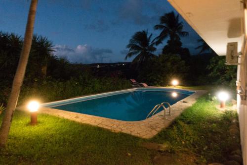 a swimming pool at night with lights in the grass at La muscade in Ferry