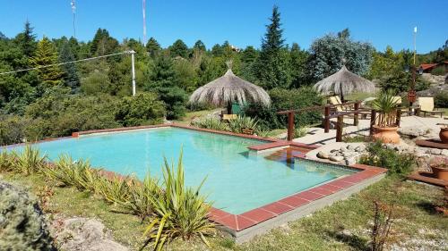 a large swimming pool in a yard with trees at Aires Serranos - Suites in La Cumbrecita
