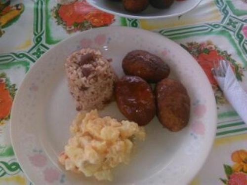 a plate of food with donuts and potatoes on a table at Posada Miss Portia in Providencia