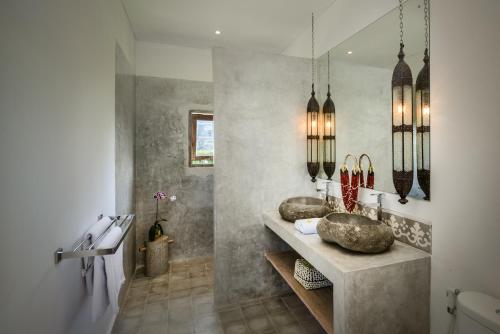 a bathroom with two sinks and two mirrors at Canggu Beach Apartments in Canggu