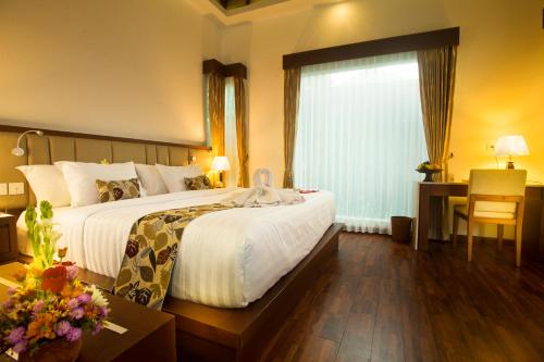 a hotel room with a large bed and a window at The Astari Villa and Residence in Jimbaran