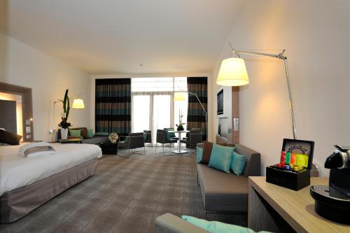 a hotel room with a bed and a living room at Novotel Avignon Centre in Avignon