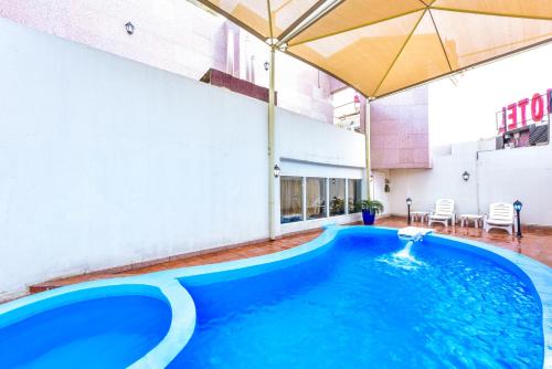 a swimming pool in a building with an umbrella at Cayam Hotel in Doha