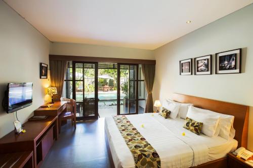 a bedroom with a bed and a desk and a television at The Astari Villa and Residence in Jimbaran