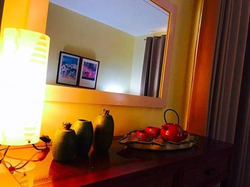 a table with vases on it with a lamp and a mirror at Ocean Villas Apart Hotel in Grand Baie