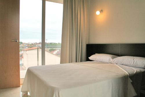 a bedroom with a white bed with a large window at L' Escala Resort in L'Escala