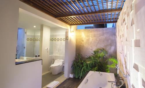 a bathroom with a tub and a toilet and a sink at The Astari Villa and Residence in Jimbaran