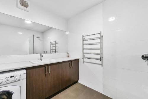 a white bathroom with a sink and a washing machine at Robe Marina Accommodation in Robe