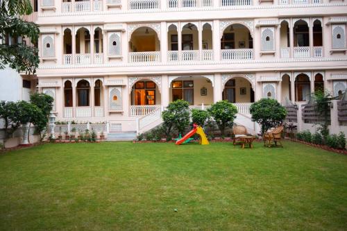 a child playing in a yard in front of a building at Hotel Arya Niwas in Jaipur