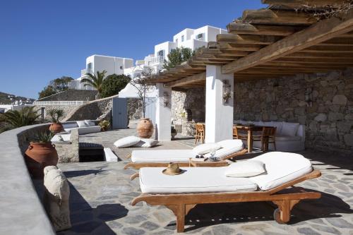 patio z białymi leżakami, stołami i budynkami w obiekcie Beachfront Mykonos Guest House w mieście Ornos