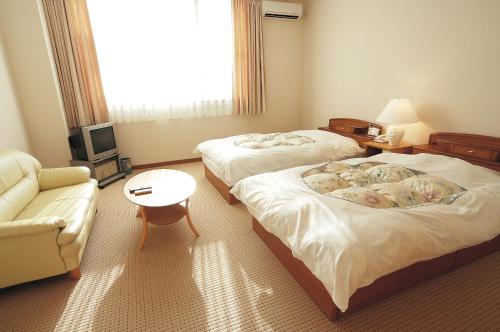 a hotel room with two beds and a couch at Watarase Onsen Hotel Yamayuri in Hongu