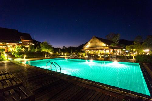 a large swimming pool at night with lights at Namkat Yorla Pa Resort in Ban Kat
