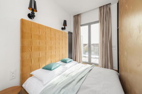 a bedroom with a large bed with a large window at Lofts Cracow Apartments - City Center in Krakow