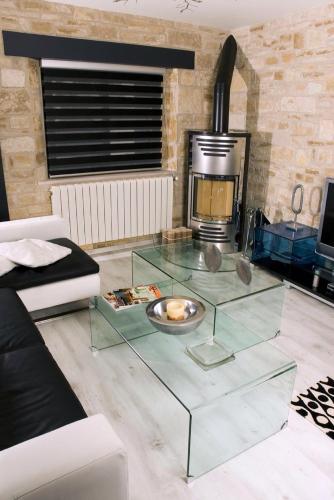 a living room with a glass coffee table in front of a fireplace at Alojamiento la Luz de la Sierra in Prádena