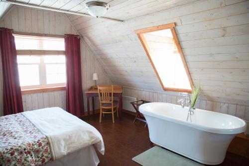 a bathroom with a bed and a tub in a room at Gîte et Centre de Santé Au Coin De La Berge B&B and Wellness Centre in Perce