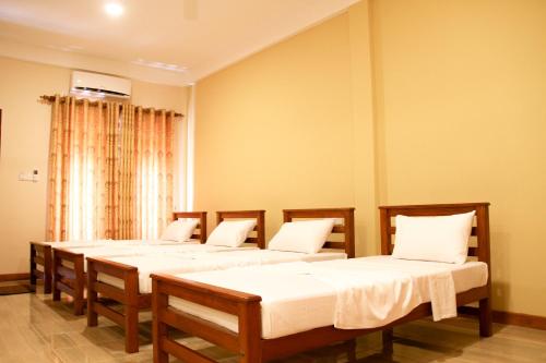 a group of four beds in a room at Hotel Nilketha Yala Tissamaharama in Tissamaharama