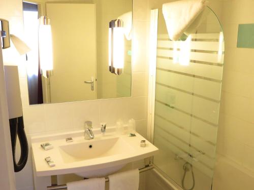 a white bathroom with a sink and a mirror at Mercure Hexagone Luxeuil in Luxeuil-les-Bains