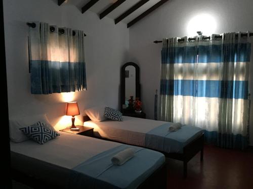 Dos camas en una habitación con cortinas y un espejo. en E-Beach Resort, en Negombo