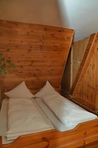 a wooden bed with white pillows in a room at Motel Eden in Zamość