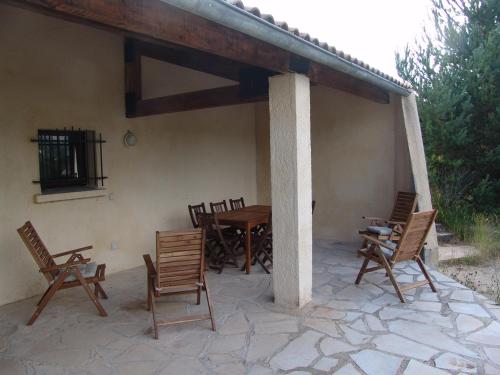 a patio with wooden chairs and a table and a table and chairs at Grand gite T5 "Sirius" de l'observatoire in Bauduen