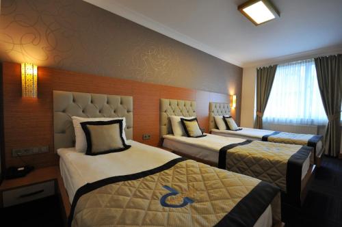 a hotel room with three beds in a room at Double Comfort Hotel in Ankara