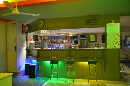 a bar with four stools in a room with a bar at Motel Eden in Zamość
